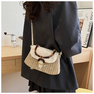 Detail of straw woven bag featuring bamboo handle and elegant floral embroidery