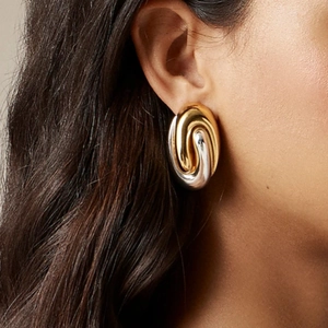 Close-up of gold and silver mixed metal twisted oval hoop earrings on a female model
