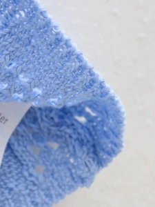 Vue macro d'un tricot bleu clair avec motif ajouré délicat et texture très douce
