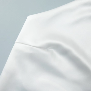 Gros plan sur le tissu en satin blanc montrant la texture lisse et les coutures