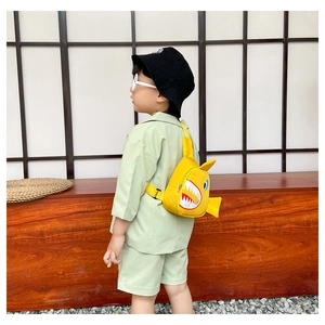 Detail view of cartoon yellow shark crossbody bag for boys worn with green casual outfit