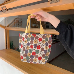 Detail of vintage floral canvas handbag with yellow straps and metal snap closure