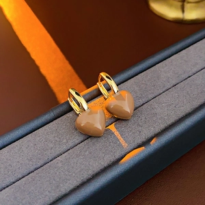 Detail of gold-plated heart earrings on a velvet display with dramatic warm lighting