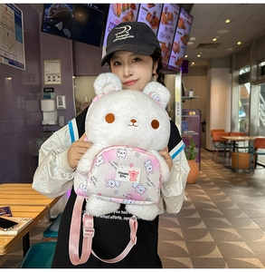 Detail of white plush rabbit backpack with pink front pocket worn in casual cafe setting