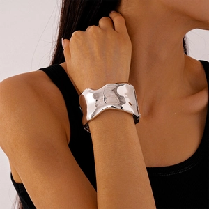 Polished silver wave cuff bracelet shown on model's wrist for a stylish fashion look