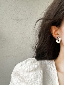 Detail view of geometric square drop earrings with silver metal clasps on a model