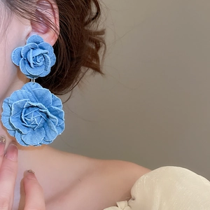 Close-up of dual-layered denim rose earrings with fringe details on model's ear
