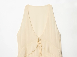 Detail of cream V-neck dress with lace-up ties and layered ruffle chiffon texture