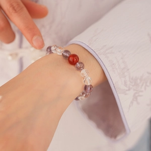 Close-up of beaded crystal bracelet with white and purple stones on person wearing embroidery