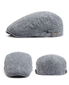Detail showing grey linen texture and bronze adjustable buckles of the flat beret cap