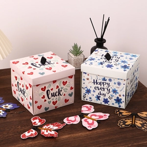 Creative butterfly explosion gift boxes with floral patterns on a warm wooden desk