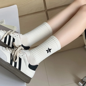 White crew socks with black stripes, star embroidery, and 'AND' text on athletic shoes