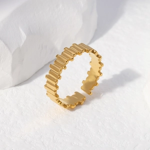 Modern geometric zigzag open ring in gold finish displayed on a textured stone base