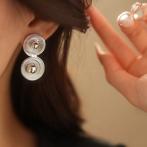 Primo piano di una modella che indossa orecchini a cerchio a doppia spirale in argento