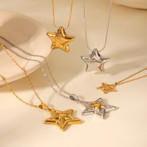 Detailed close-up of gold and silver star pendant necklaces on a ceramic tray