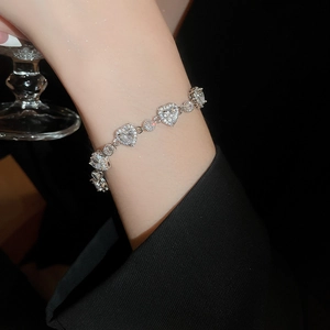 Macro shot of silver heart-shaped bracelet featuring sparkling cubic zirconia on a wrist