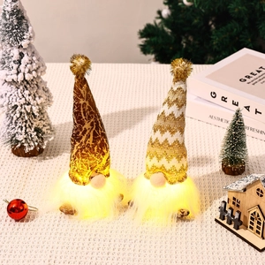 Detail of lit Christmas gnomes with golden knit hats and LED glowing warm lights