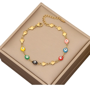 Gold chain bracelet with colorful evil eye beads and heart charms on a jewelry box