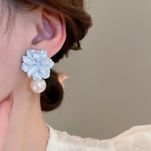 Close-up of light blue resin flower earrings with white pearl pendants on a model