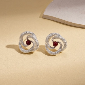 Detailed macro shot of vintage silver textured earrings with deep red pearl centerpieces