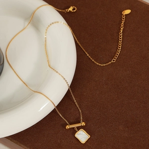 18K gold plated titanium necklace with square white shell pendant on a ceramic dish