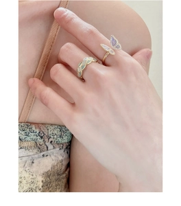 Detail of vintage butterfly and woven gold rings with purple crystal and enamel inlay
