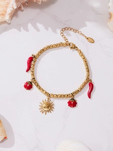 Detail showing gold stainless steel beaded bracelet with red chili and ladybug charms