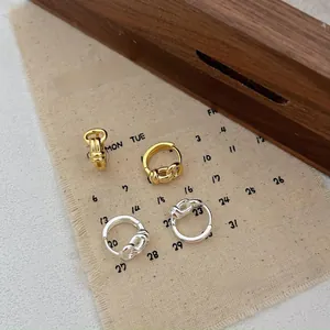 Detailed view of silver and gold knotted chain hoop earrings on a vintage calendar cloth