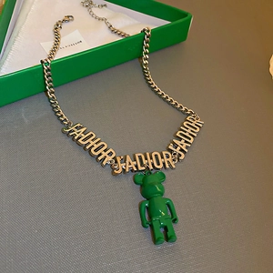 Gros plan détaillé du collier doré avec pendentif ours vert et breloques en lettres