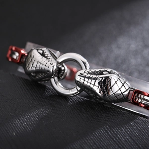 Macro view of silver stainless steel snake scale bracelet with red details and snake head