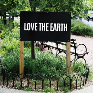 Detail of waterproof outdoor sign with LOVE THE EARTH text on park lawn background