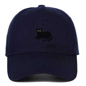 Detail of yellow-eyed black cat embroidery on navy blue cotton baseball cap