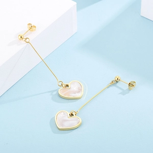 Detailed view of long heart-shaped drop earrings with golden finish and pearl shell inlay