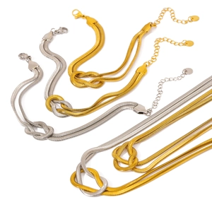Gold and silver snake chain necklaces with central knot detail on a white background