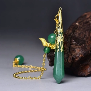 Macro detail of hexagonal green gemstone pendant with gold filigree cap on dark wood