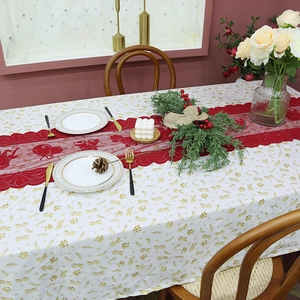 Red Christmas lace table runner with bell patterns on a golden leaf tablecloth