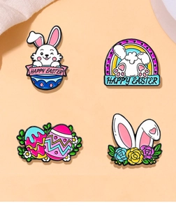 Set of four colorful Easter enamel pins featuring rabbits and eggs on orange background