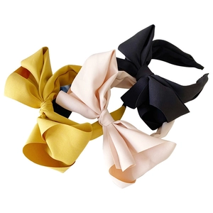 Three elegant fabric bow headbands in yellow, pink and black on a white background