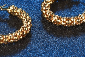 Macro view of gold hoop earrings with embossed grainy texture and metallic luster