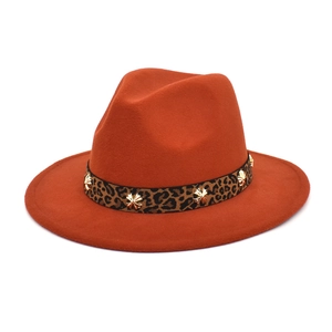 Close-up of rust-orange fedora hat with leopard band and gold cross metal studs