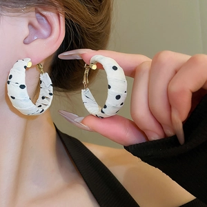 Detail of large polka dot fabric wrapped hoop earrings on model for a trendy retro style