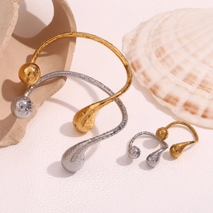 Detail of 18K gold and silver open bracelets with teardrop ends on beach shells