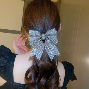 Close-up of sparkling rhinestone bow hair clip on long wavy hair with star-like shine