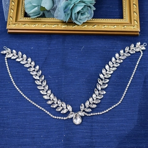 Close-up of silver crystal leaf bridal headpiece with teardrop pendant on blue fabric