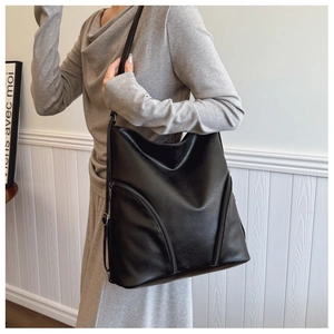 Detailed close-up of a large black soft PU leather hobo bag with zipper accents on model