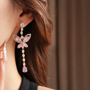 Detailed view of pink butterfly earrings with teardrop gems worn by a model