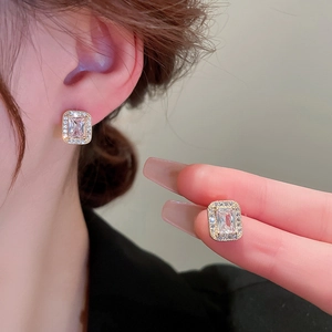 Close-up of gold-plated square zircon stud earrings with micro-pave halo on ear