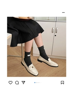 Detail of dark grey ribbed slouch socks with a fabric label worn with beige loafers