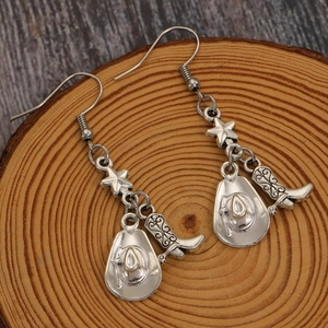 Détail de boucles d'oreilles western argentées avec chapeau de cowboy et bottes