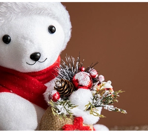 Close-up of a white plush Christmas bear with red scarf holding a pine cone burlap bag